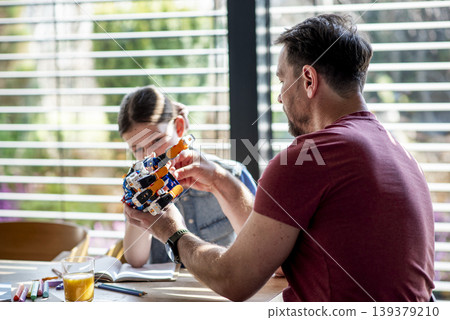 Father teaching daughter robotics at home while homeschooling with educational toy. Father teaching daughter robotics at home while homeschooling with educational toy. 139379210