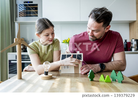 Father teaching daughter about renewable energy and ecology at home. 139379229