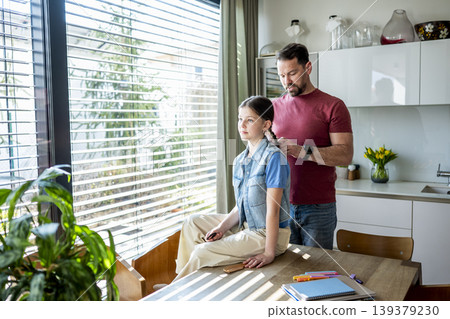 Dad brushing daughter hair and making braid at home. 139379230