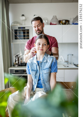 Dad brushing daughter hair and making braid at home. Dad brushing daughter hair and making braid at home. 139379232