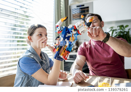 Father teaching daughter robotics at home while homeschooling with educational toy. Father teaching daughter robotics at home while homeschooling with educational toy. 139379261