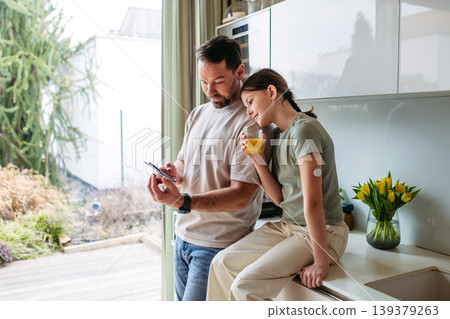 Diabetic girl and father checking her blood sugar level on phone. Diabetic girl and father checking her blood sugar level on phone. 139379263