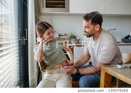 Dad assisting diabetic teen girl with daily insulin treatment routine. Dad assisting diabetic teen girl with daily insulin treatment routine. 139379269