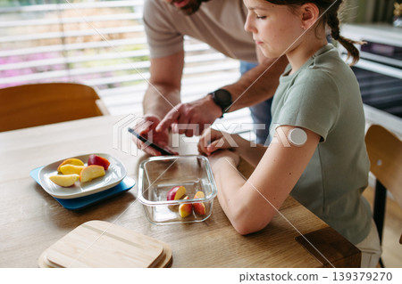 Parent helping diabetic daughter understand nutrition and sugar content. Parent helping diabetic daughter understand nutrition and sugar content. 139379270