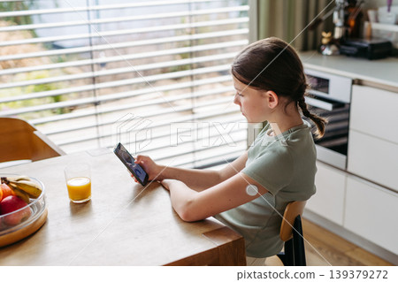 Teen girl with diabetes checking glucose results on smartphone after CGM scan. 139379272