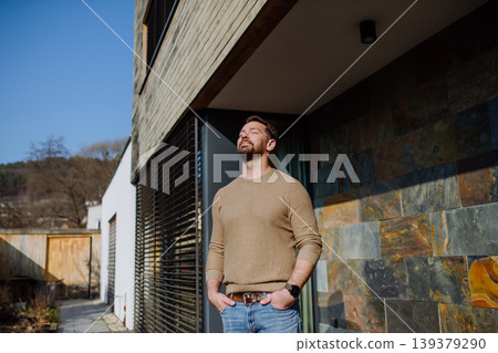Man enjoying warm spring sunlight on face while standing outside. Man enjoying warm spring sunlight on face while standing outside. 139379290