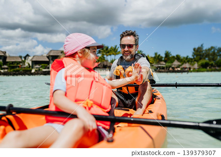 Father kayaking with daughter on calm sea during family summer vacation. Father kayaking with daughter on calm sea during family summer vacation. 139379307