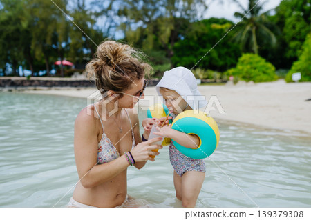 Mother playing in sea water with little daughter. Mother playing in sea water with little daughter. 139379308