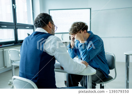 Teacher supporting struggling student. Boy confiding in a teacher. Teacher supporting struggling student. Boy confiding in a teacher. 139379350