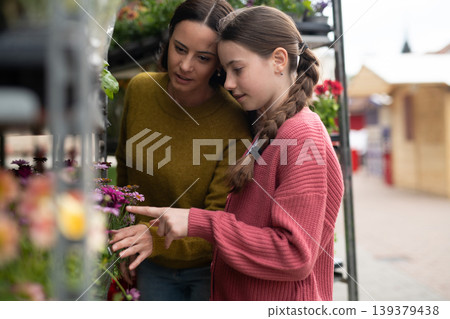 Mother and daughter choosing flowers at market. Mother and daughter choosing flowers at market. 139379438