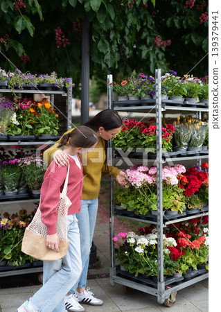 Mother and daughter choosing flowers at market. 139379441