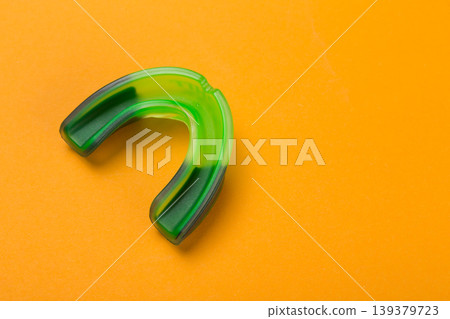Professional green and black gum shield on a bright orange background for sports marketing. 139379723