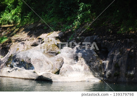 A tranquil riverside landscape with exposed rock faces. A tranquil riverside landscape with exposed rock faces. 139379798