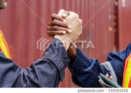 Close-up of Caucasian male and Black female logistics workers in solidarity handshake at Asian shipping port. Close-up of Caucasian male and Black female logistics workers in solidarity handshake at Asian shipping port. 139381038