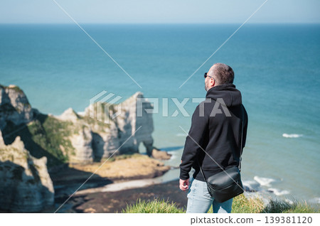 Man stands and look at cliffs and Waters of Etretat Man stands and look at cliffs and Waters of Etretat 139381120