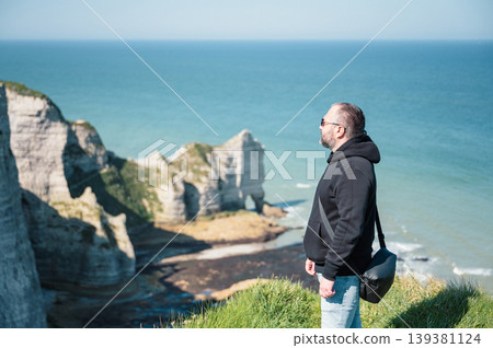 Man stands and look at cliffs and Waters of Etretat 139381124