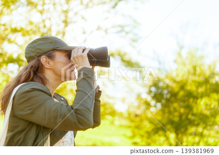 Woman Exploring Nature with Binoculars in Lush Forest Woman Exploring Nature with Binoculars in Lush Forest 139381969