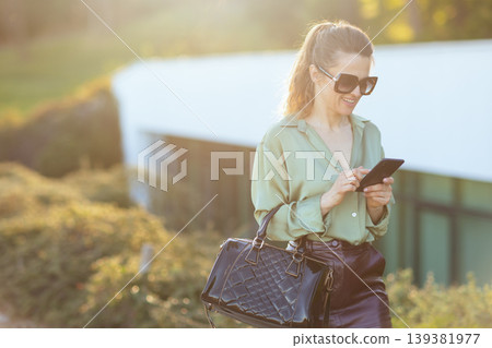 Stylish Urban Woman Checking Smartphone at Golden Hour Stylish Urban Woman Checking Smartphone at Golden Hour 139381977