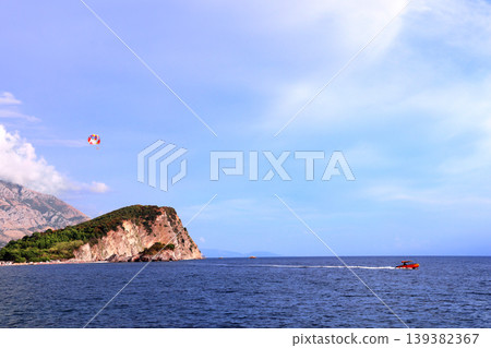 Picturesque view of Adriatic sea, St. Nicholas Island and tourists on a parachute, Budva, Montenegro. Topic of summer vacation, leisure for adventure tourist. Popular tourist pastime with parascending Picturesque view of Adriatic sea, St. Nicholas Island and tourists on a parachute, Budva, Montenegro. Topic of summer vacation, leisure for adventure tourist. Popular tourist pastime with parascending 139382367