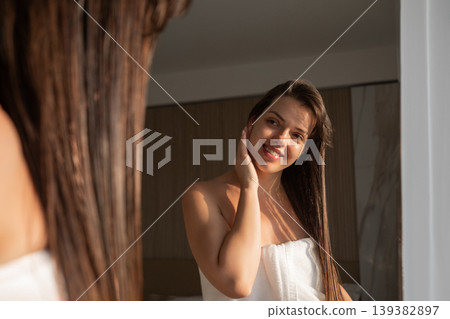 Pretty woman touching face and long wet hair in mirror reflection glowing skin beauty skincare and haircare routine portrait Pretty woman touching face and long wet hair in mirror reflection glowing skin beauty skincare and haircare routine portrait 139382897