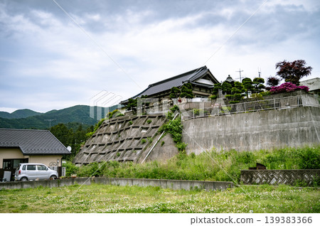 山坡上，一座傳統的日式房屋由網格狀的混凝土斜坡支撐。 139383366
