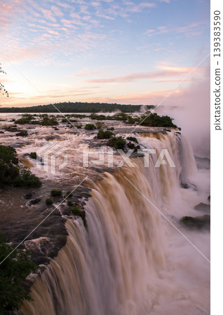 Majestic iguazu falls cascade over cliff during breathtaking sunrise Majestic iguazu falls cascade over cliff during breathtaking sunrise 139383590