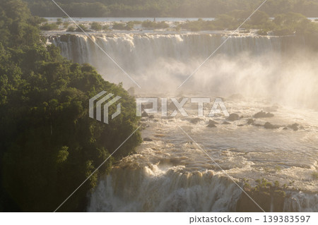 Mesmerizing iguazu falls waterfall cascading water creating mist in lush nature landscape 139383597