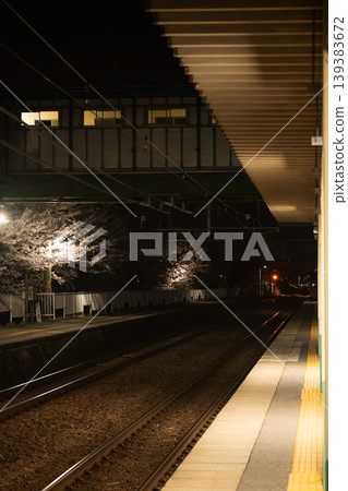 夜晚從車站月台上可以欣賞到燈光璀璨的櫻花和鐵軌的美景。 夜晚從車站月台上可以欣賞到燈光璀璨的櫻花和鐵軌的美景。 139383672