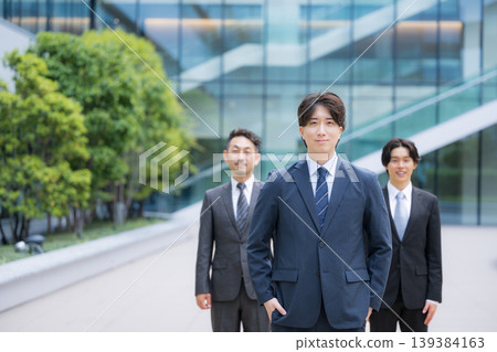 Three people, including consultants, in a business setting, looking directly at the camera and smiling. 139384163
