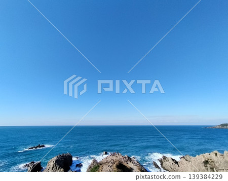 藍天下,海浪拍打著岩石,景色壯麗。 藍天下,海浪拍打著岩石,景色壯麗。 139384229