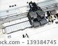Close-up open inkjet printer showing the printhead and cartridge assembly on rails, internal hardware, mechanisms and parts for repair, maintenance, diagnostics and technical documentation. 139384745