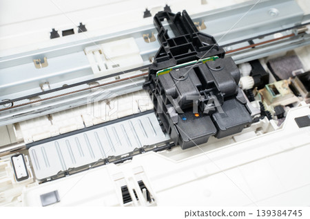 Close-up open inkjet printer showing the printhead and cartridge assembly on rails, internal hardware, mechanisms and parts for repair, maintenance, diagnostics and technical documentation. Close-up open inkjet printer showing the printhead and cartridge assembly on rails, internal hardware, mechanisms and parts for repair, maintenance, diagnostics and technical documentation. 139384745