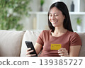 Happy asian woman buying online using cellphone and card 139385727