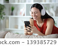 Happy asian woman watching media content on smart phone 139385729