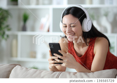 Happy asian woman watching media content on smart phone Happy asian woman watching media content on smart phone 139385729