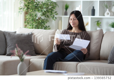 Satisfied asian woman reading letter on a couch at home 139385732
