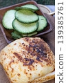 a decadent, cheese-crowned toastie, its surface transformed into a mosaic of molten ivory and deep, toasted amber. This savory warmth is perfectly balanced by a hand-carved wooden bowl filled with 139385761