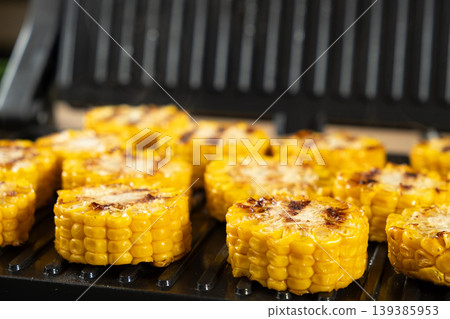 Appetizing Yellow Corn Rounds Grilling on Indoor Contact Grill Appetizing Yellow Corn Rounds Grilling on Indoor Contact Grill 139385953
