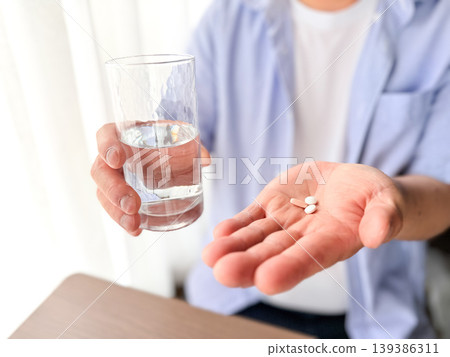 Hands taking medicine with water 139386311