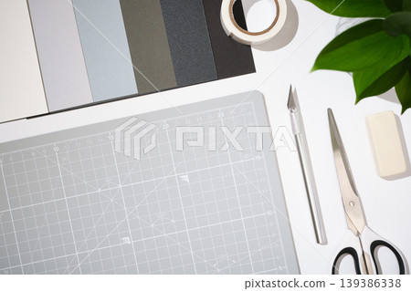 Craft workspace with cutting mat, utility knife, scissors, color samples and stationery on clean white background. Copyspace Craft workspace with cutting mat, utility knife, scissors, color samples and stationery on clean white background. Copyspace 139386338