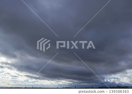 Stormy dark thunderclouds gather in the gloomy sky over the city. Cloudy sky with dark gray rain clouds. Stormy dark thunderclouds gather in the gloomy sky over the city. Cloudy sky with dark gray rain clouds. 139386383