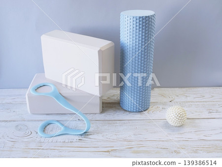 Equipment for yoga and pilates. Yoga blocks, roller, expander and massage ball on a wooden surface. Equipment for yoga and pilates. Yoga blocks, roller, expander and massage ball on a wooden surface. 139386514