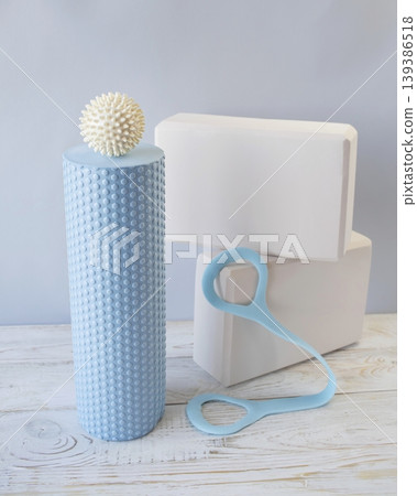 Equipment for yoga and pilates. Yoga blocks, roller, expander and massage ball on a wooden surface. 139386518
