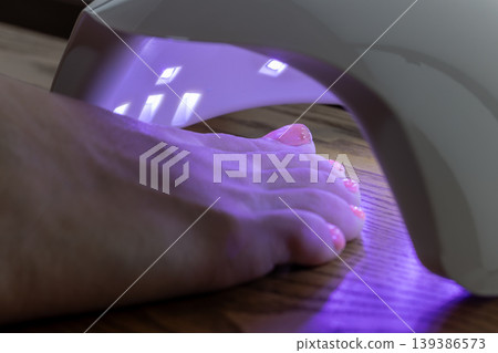 I'm shining an LED light on the gel nail polish I applied to my toenail. I'm shining an LED light on the gel nail polish I applied to my toenail. 139386573