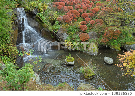A clear autumn waterfall carved into the rock face; a vibrant Japanese garden where the freshly trimmed hedges and spray create a dynamic scene. A clear autumn waterfall carved into the rock face; a vibrant Japanese garden where the freshly trimmed hedges and spray create a dynamic scene. 139386580