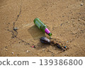 Glass bottle lying on sand showing beach pollution 139386800