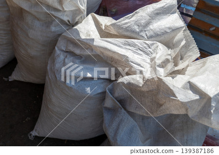 Bags filled with construction waste are stacked at a construction site. The location is busy with activity during daylight hours Bags filled with construction waste are stacked at a construction site. The location is busy with activity during daylight hours 139387186