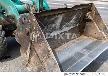Excavator bucket is lifted and ready for earth moving at a busy construction site during daytime operation of heavy machinery 139387195