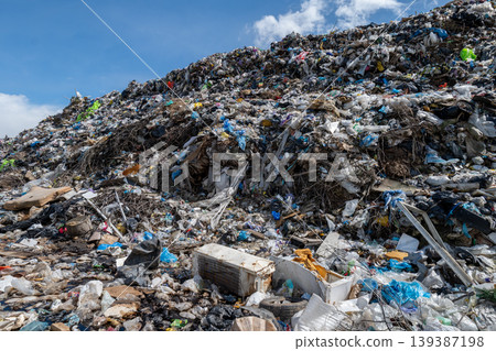 A large landfill site shows a mix of household waste including plastics and materials. Sunlight shines on the refuse spread out 139387198