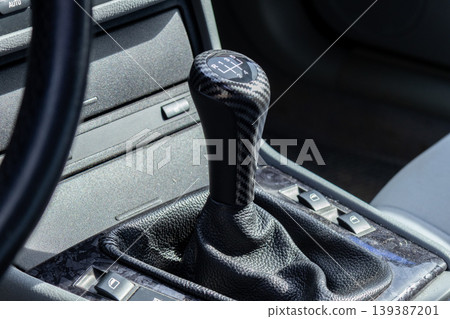 Focus on gear shift and control buttons inside a modern car parked on the street during daylight hours 139387201